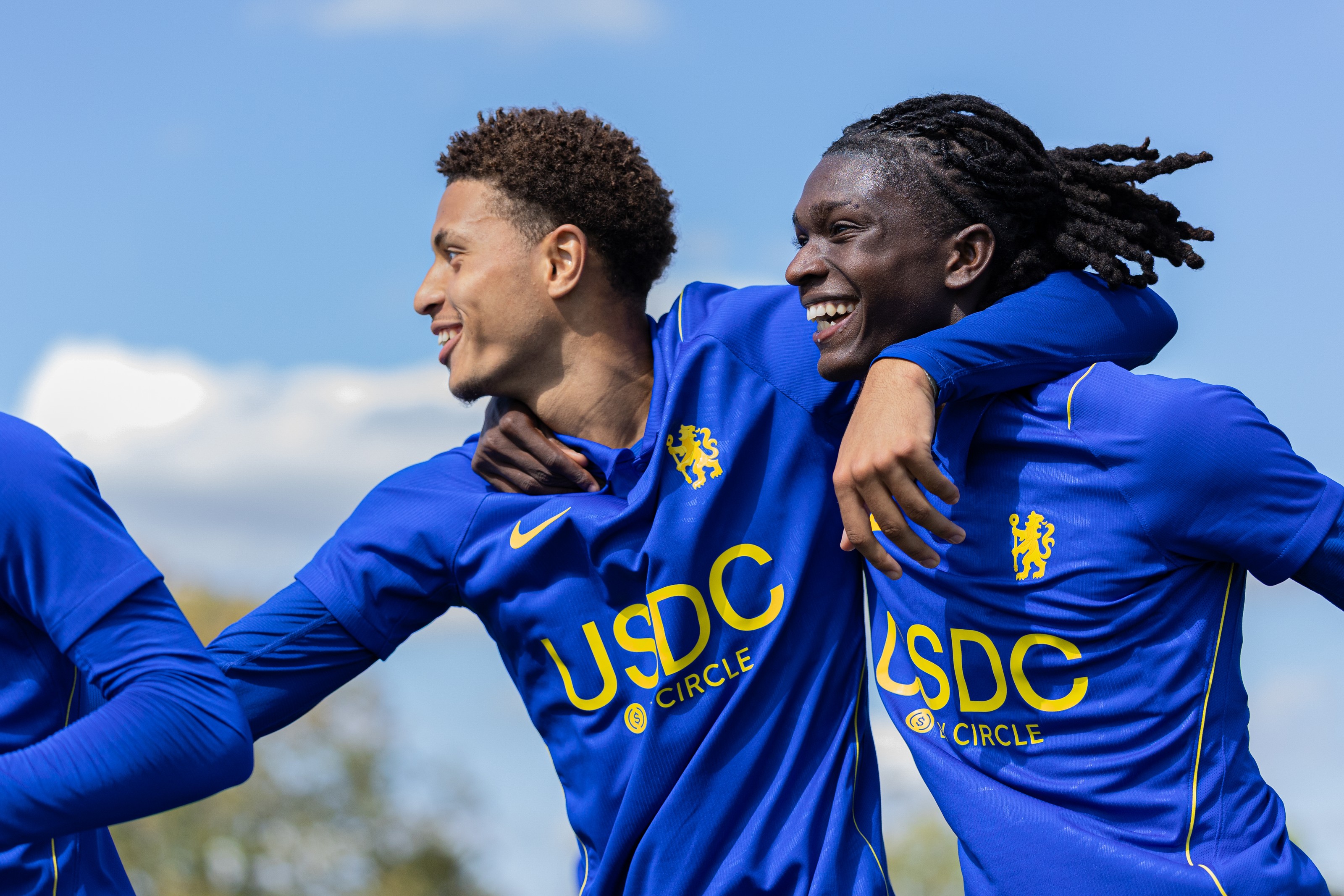 Two Chelsea academy players laughing arm in arm after a goal