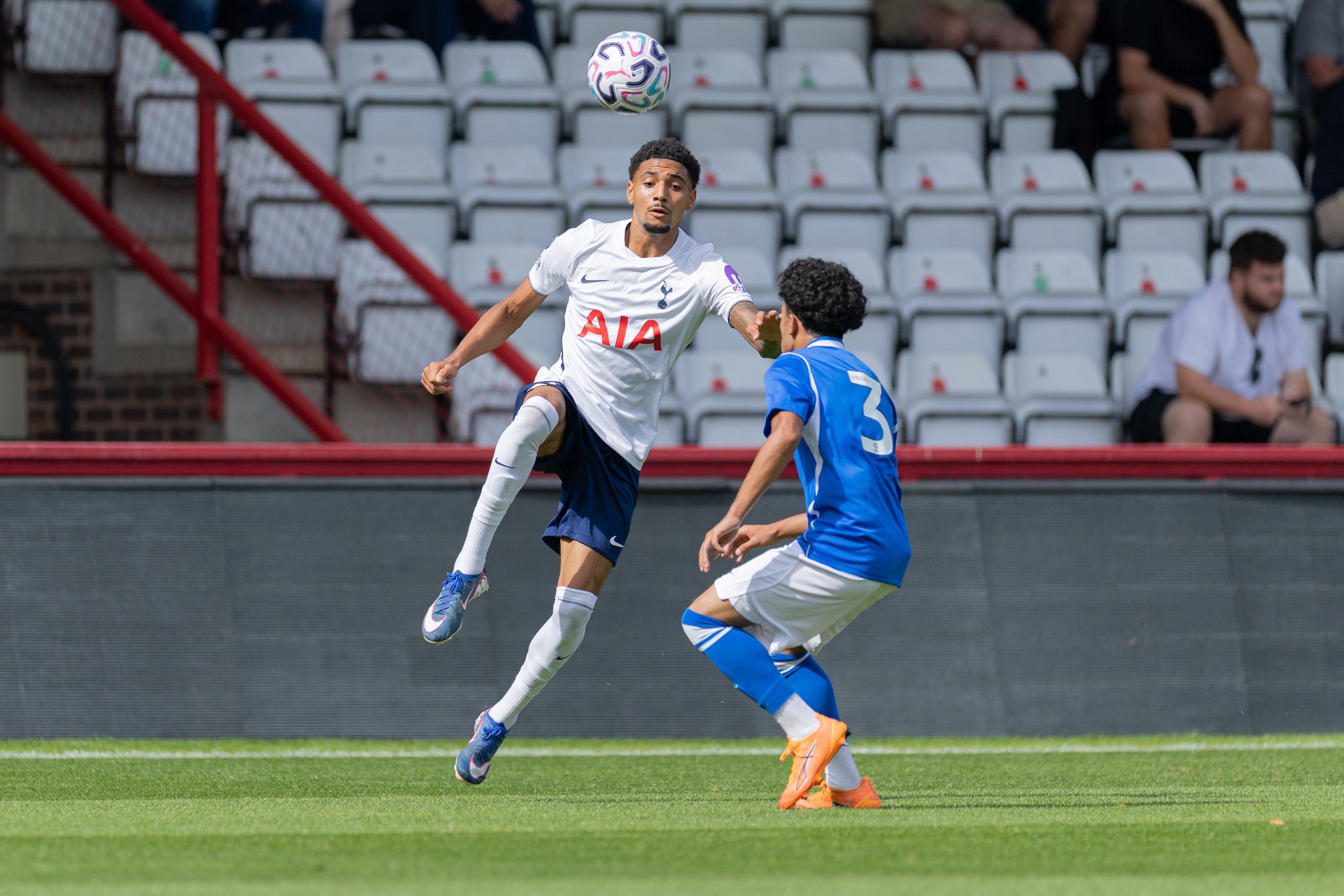 Tottenham U21 player leaping to control the ball in front of the stand
